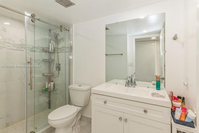 bathroom with toilet, vanity, and a shower with shower door