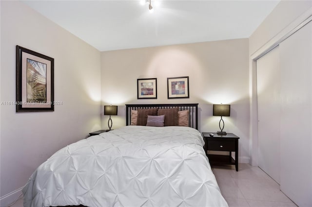 bedroom featuring track lighting, light tile patterned floors, and a closet