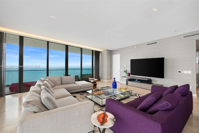 living room featuring a water view, floor to ceiling windows, and light hardwood / wood-style flooring