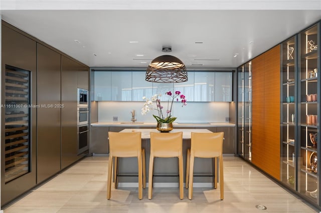 kitchen featuring sink, a breakfast bar, appliances with stainless steel finishes, wine cooler, and a kitchen island