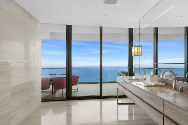 bathroom with vanity, a water view, a wealth of natural light, and a wall of windows