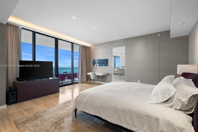 bedroom featuring light wood-type flooring, a wall of windows, and access to outside