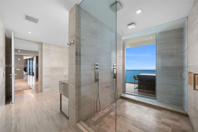 bathroom featuring tile walls, tiled shower, and a water view