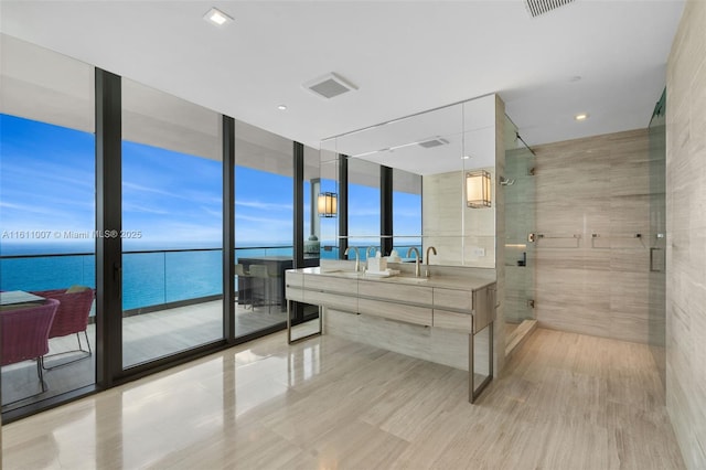 bathroom featuring vanity, a water view, a wall of windows, and a shower with shower door