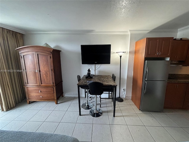 kitchen featuring range hood, light tile patterned floors, crown molding, and stainless steel fridge