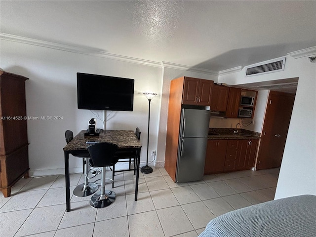 kitchen featuring stainless steel refrigerator, light tile patterned floors, and crown molding