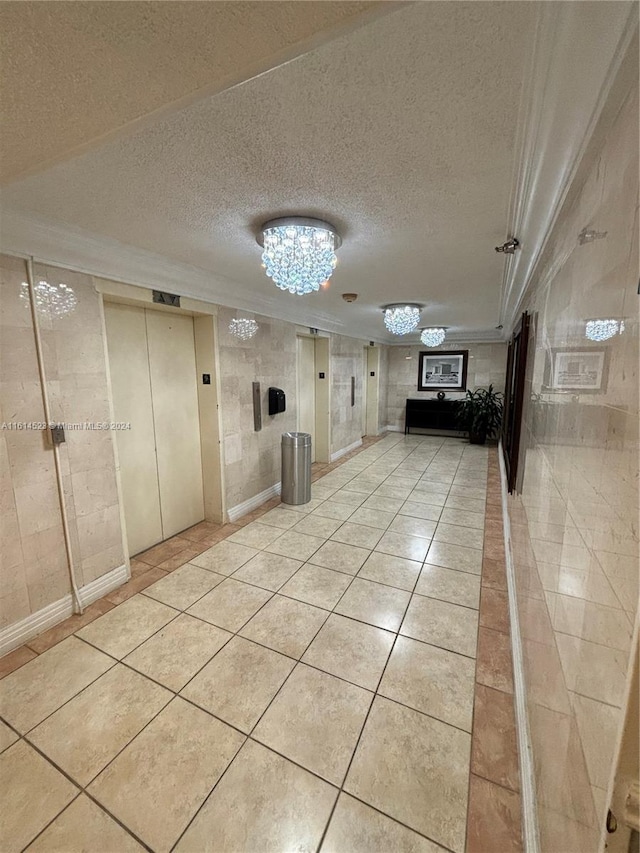 corridor with elevator, a textured ceiling, and light tile patterned floors