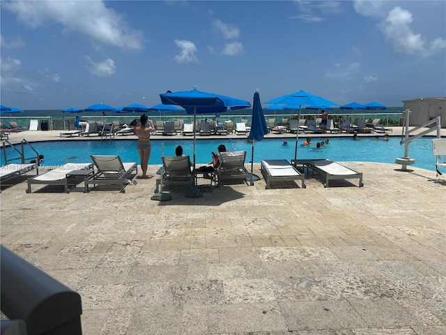 view of pool with a water view and a patio