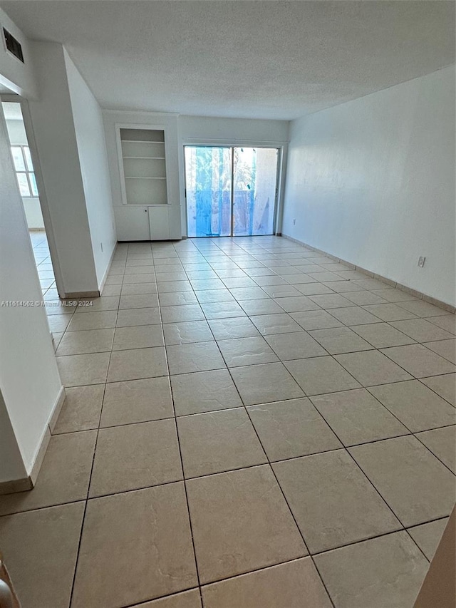 tiled spare room featuring built in features and a textured ceiling