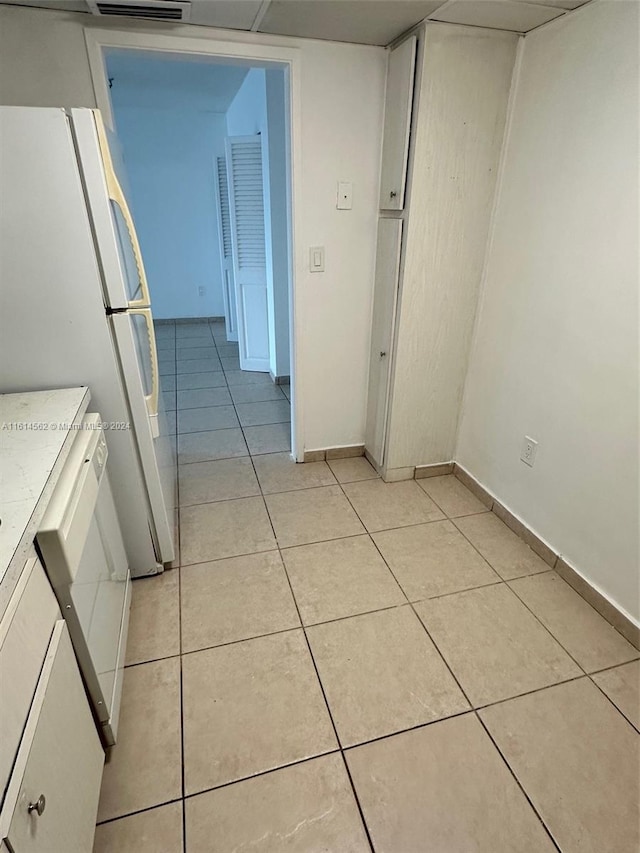 kitchen with white cabinets, light tile patterned flooring, and white fridge