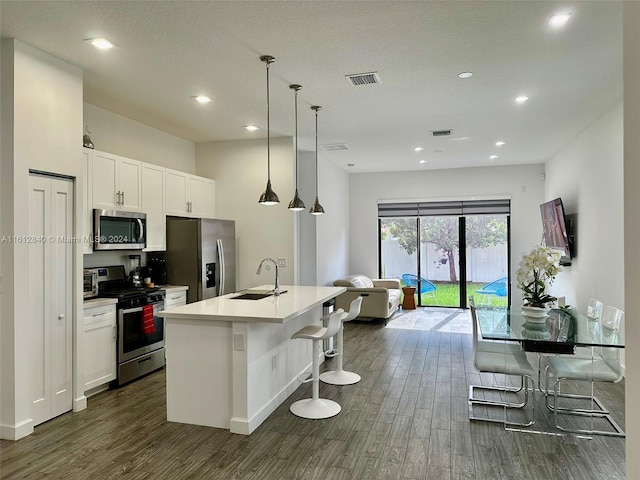 kitchen featuring dark hardwood / wood-style floors, a center island with sink, a kitchen bar, stainless steel appliances, and sink