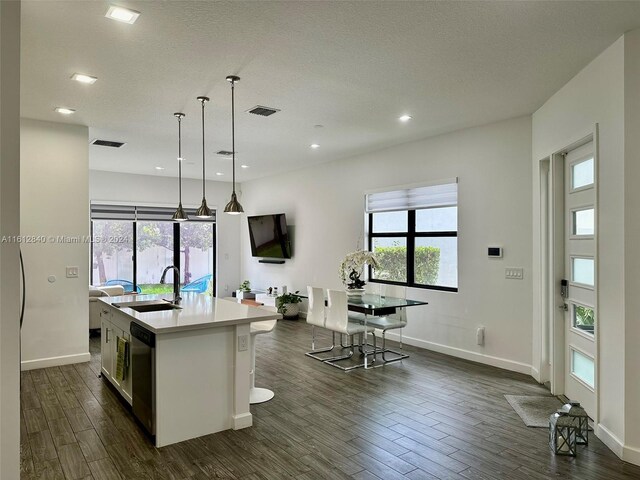 kitchen featuring pendant lighting, dark hardwood / wood-style flooring, a center island with sink, and sink