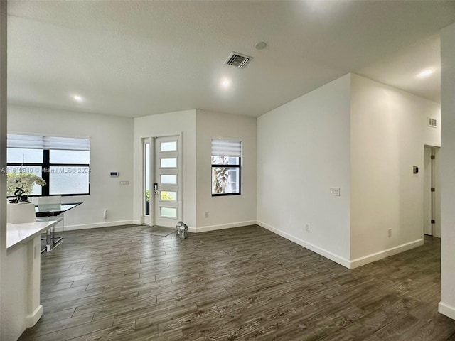 unfurnished living room with a textured ceiling and dark wood-type flooring