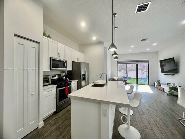 kitchen featuring dark wood-type flooring, sink, decorative light fixtures, and appliances with stainless steel finishes