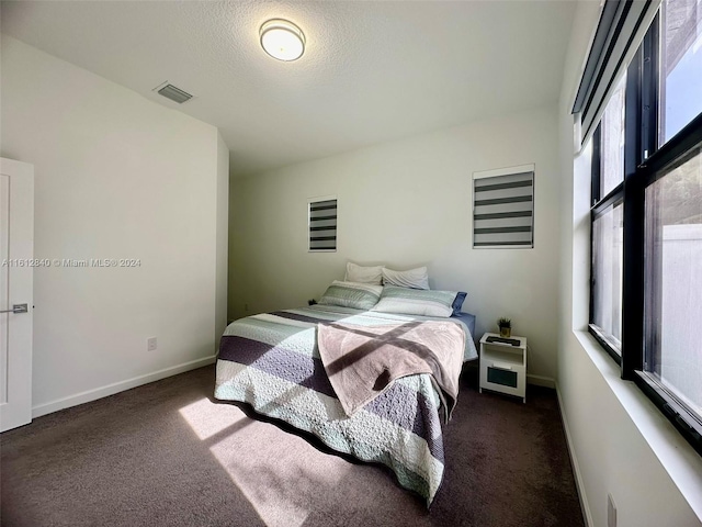 bedroom with dark carpet and a textured ceiling