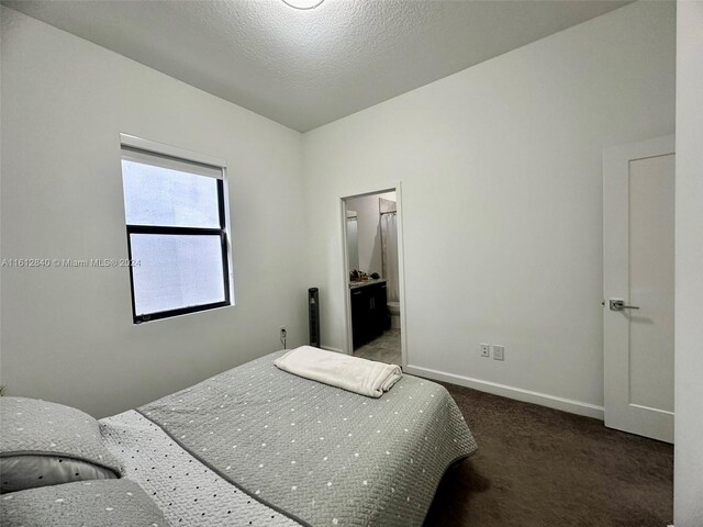 bedroom featuring dark carpet and a textured ceiling