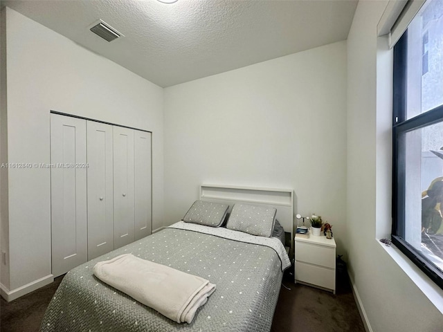 carpeted bedroom featuring a closet and a textured ceiling