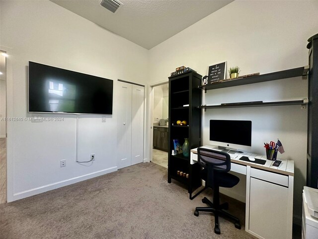 carpeted home office featuring a textured ceiling