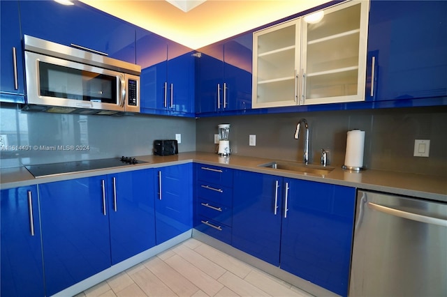 kitchen with blue cabinetry, stainless steel appliances, and sink