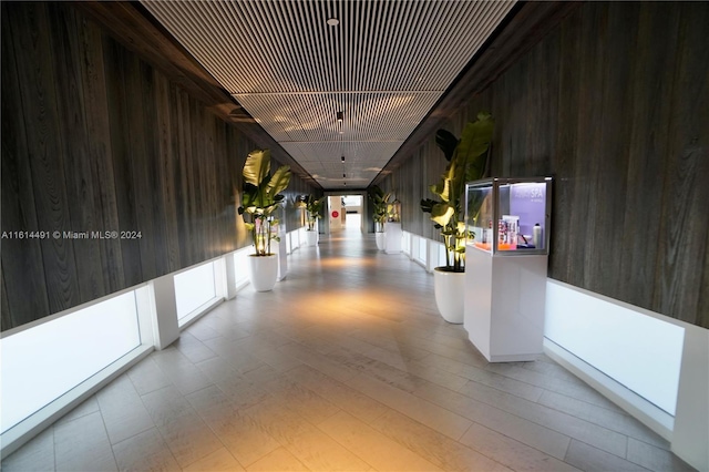 corridor featuring light wood-type flooring and wooden walls