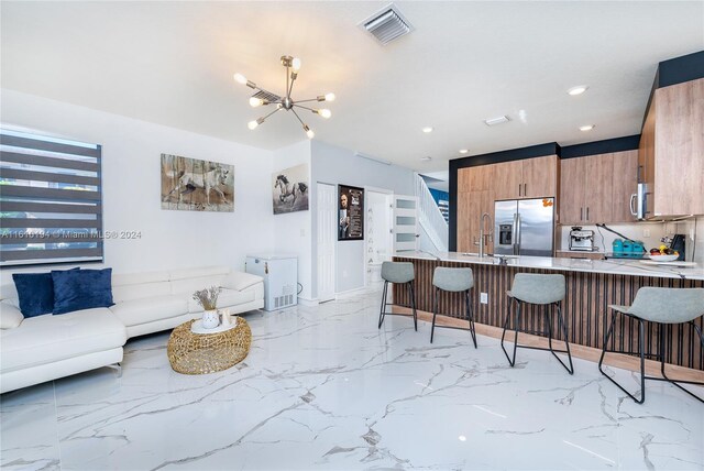 kitchen with a breakfast bar area, appliances with stainless steel finishes, a chandelier, light tile patterned floors, and kitchen peninsula