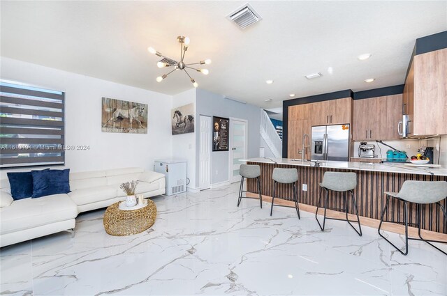 kitchen with stainless steel appliances, light tile patterned floors, a kitchen breakfast bar, a chandelier, and kitchen peninsula