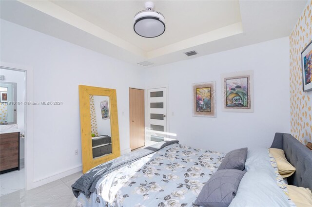 bedroom with light tile patterned floors and a raised ceiling