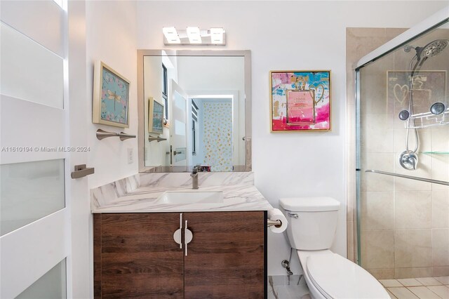 bathroom with a shower with shower door, vanity, and toilet