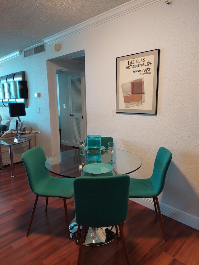 dining space with ornamental molding, wood-type flooring, and a textured ceiling