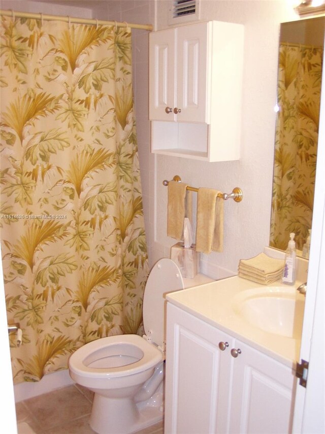 bathroom with tile floors, toilet, and vanity with extensive cabinet space