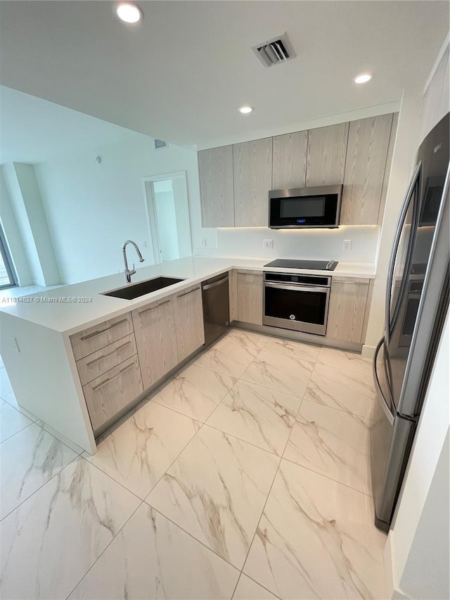 kitchen featuring stainless steel appliances, sink, and light tile flooring