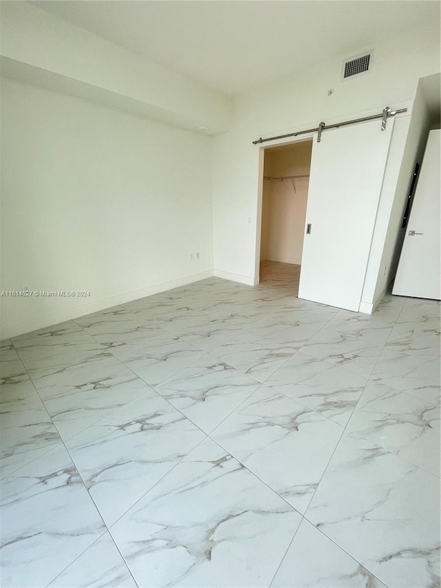 unfurnished bedroom featuring a barn door and light tile flooring