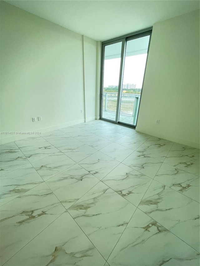 spare room featuring tile flooring and floor to ceiling windows