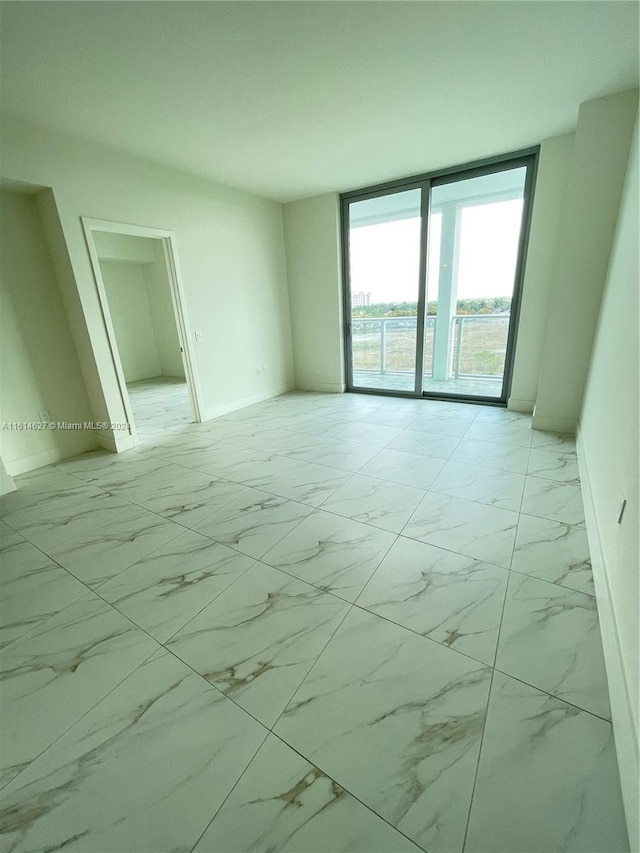 tiled spare room featuring floor to ceiling windows