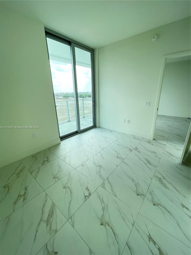 empty room featuring floor to ceiling windows and tile floors