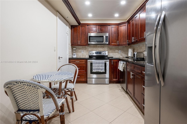 kitchen with decorative backsplash, dark stone counters, stainless steel appliances, sink, and light tile patterned floors