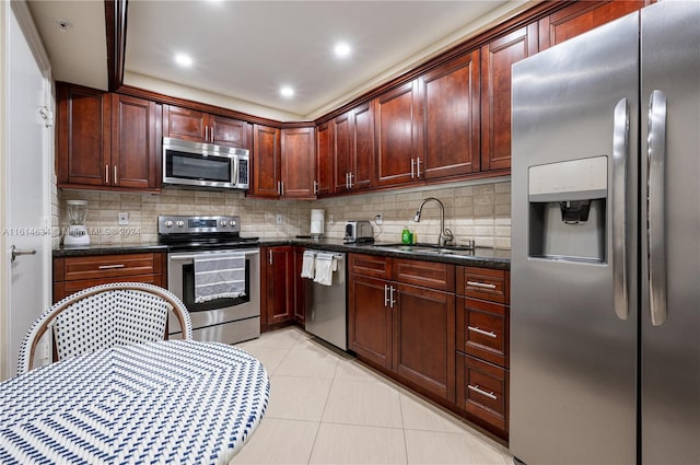 kitchen featuring decorative backsplash, appliances with stainless steel finishes, sink, light tile patterned floors, and dark stone countertops