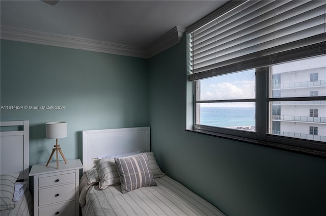 bedroom with a water view and crown molding