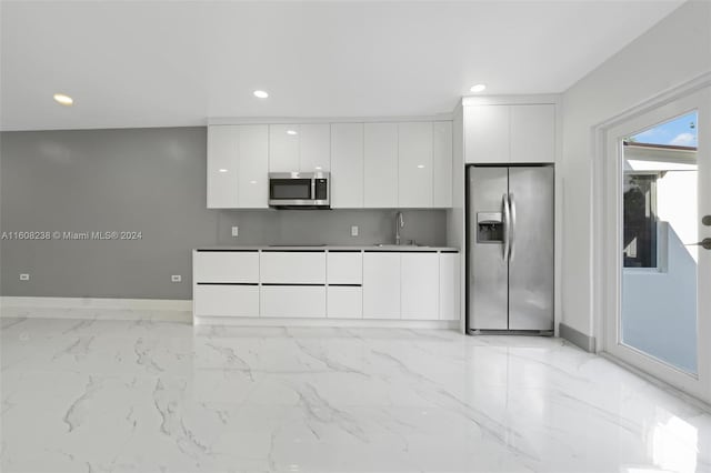 kitchen featuring white cabinetry, decorative backsplash, sink, appliances with stainless steel finishes, and light tile patterned floors