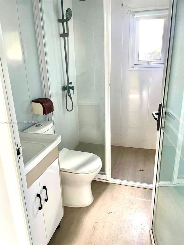 bathroom with vanity, a shower with door, hardwood / wood-style flooring, and toilet