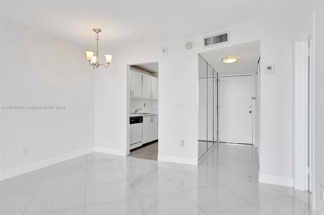 unfurnished room featuring sink, an inviting chandelier, and light tile floors