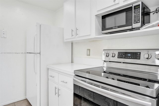 kitchen featuring appliances with stainless steel finishes, white cabinets, and light tile floors