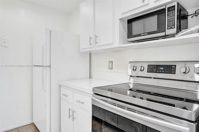 kitchen with light tile patterned floors, stainless steel appliances, and white cabinets