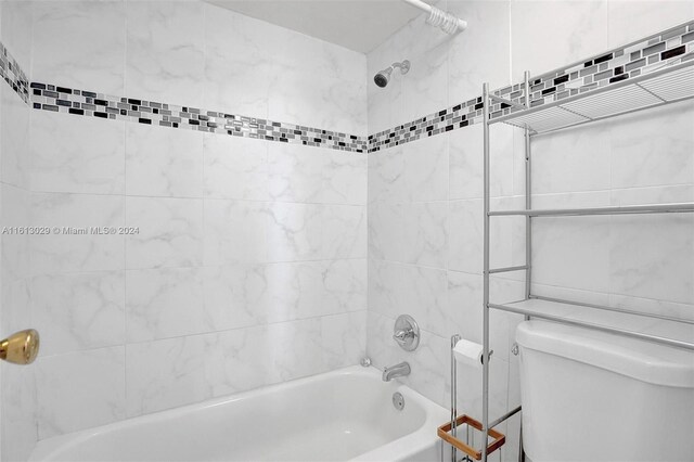 bathroom with tiled shower / bath combo and toilet