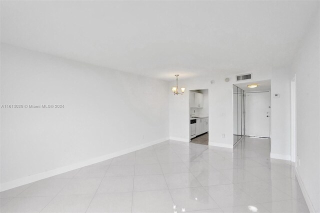 tiled spare room with a chandelier