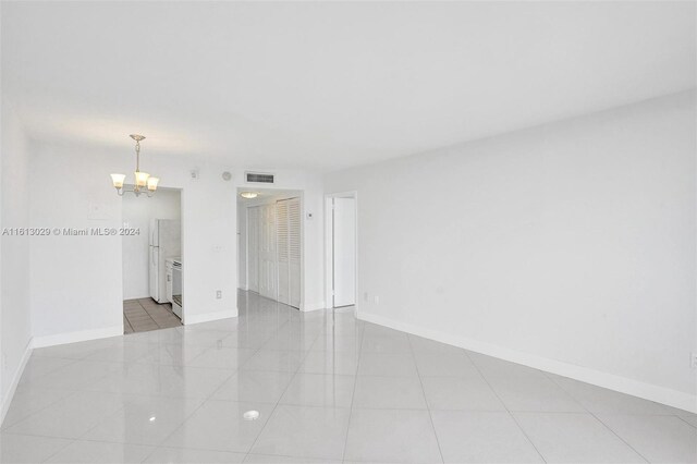 empty room with a chandelier and light tile floors