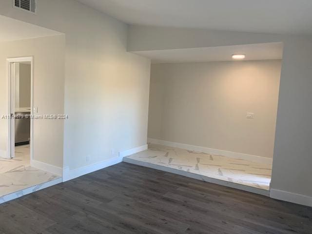 empty room featuring vaulted ceiling and dark hardwood / wood-style floors