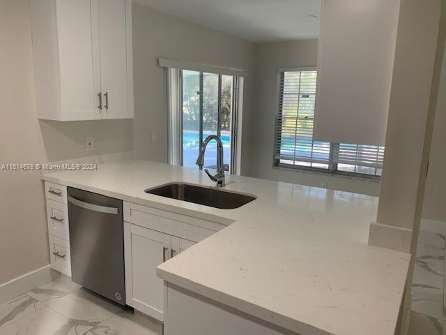 kitchen with kitchen peninsula, white cabinetry, stainless steel dishwasher, and sink