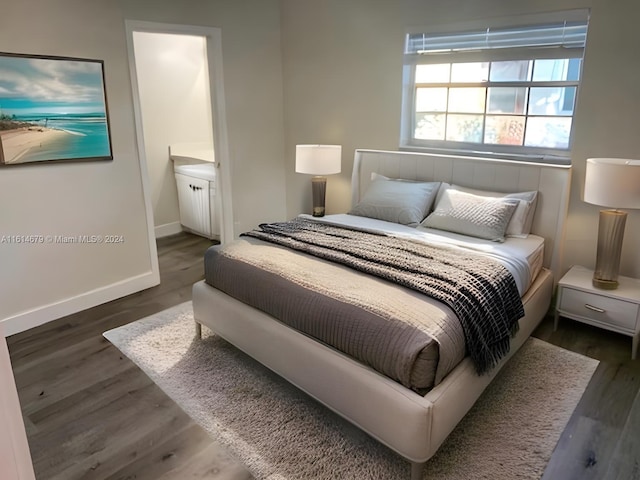 bedroom with dark wood-type flooring and connected bathroom