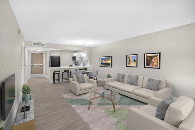 living room featuring sink and light hardwood / wood-style flooring